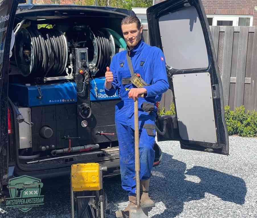 Een tevreden monteur met opgestoken duim naast de bestelbus, slim ingrijpen bespaart kosten bij een verstopte afvoer in Amsterdam
