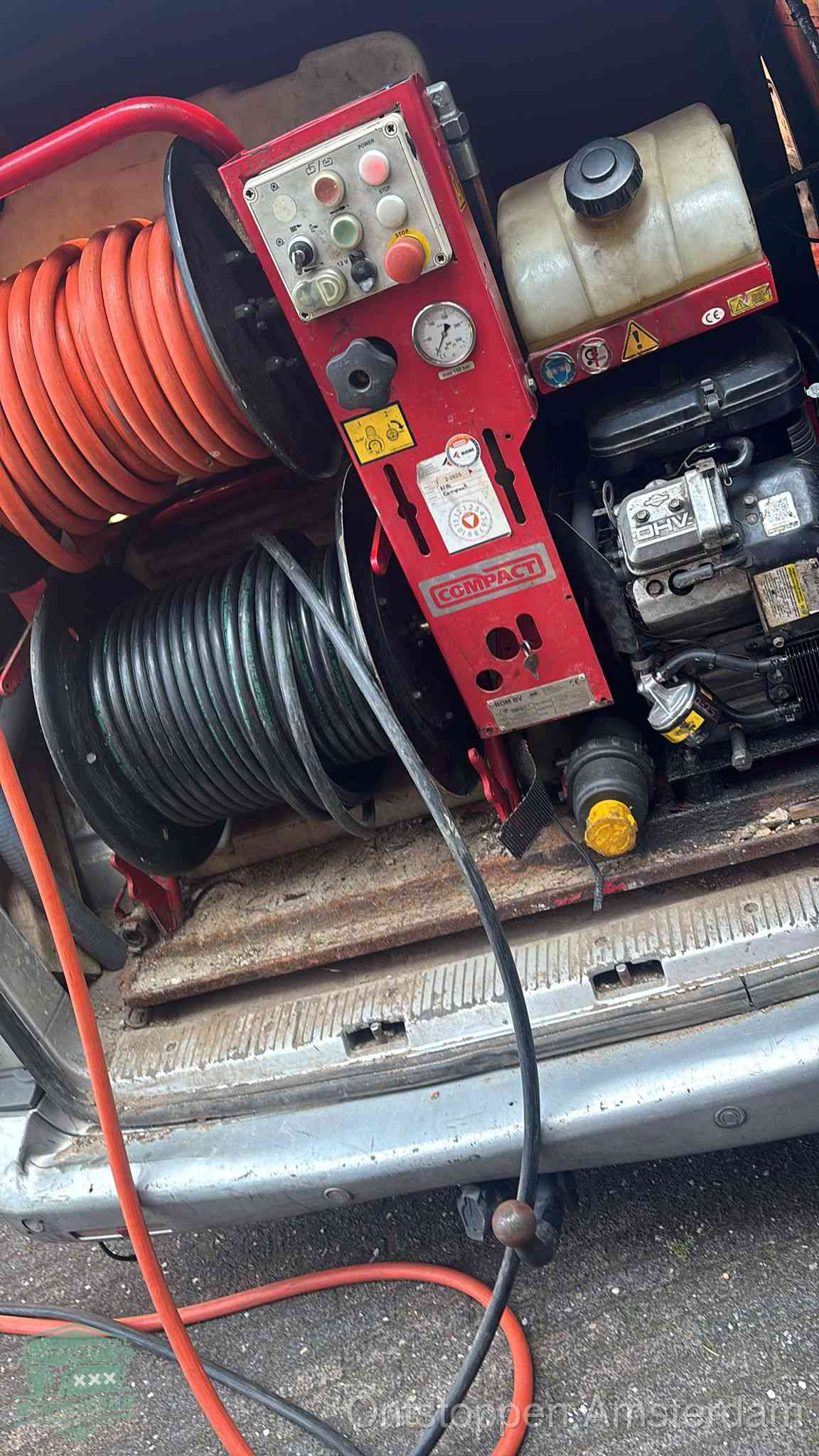 Een rood hogedruk-rioolreinigingstoestel in de laadbak van de bedrijfsbus, apparatuur voor een hardnekkige afvoerverstopping in Amsterdam