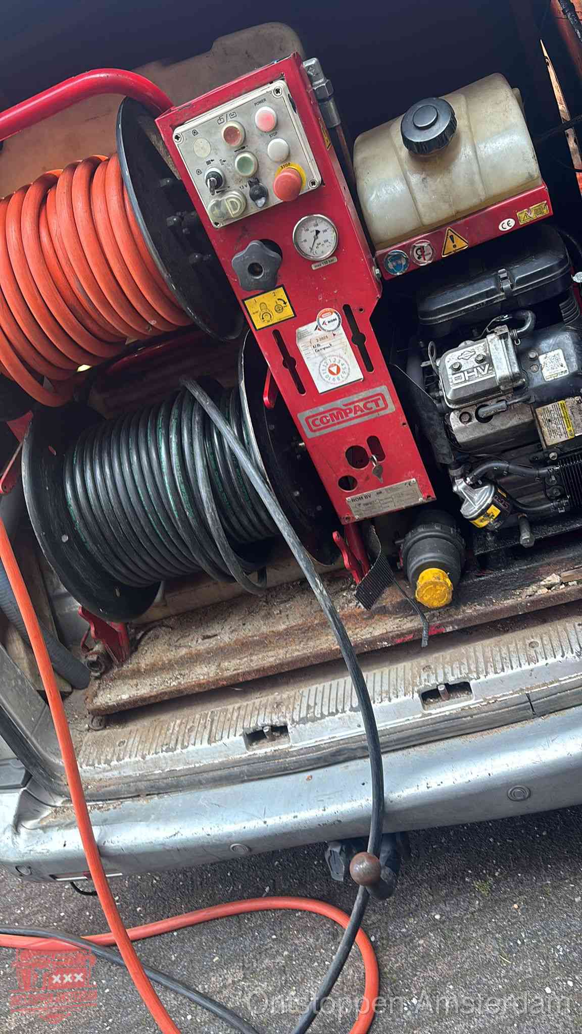 Een rood hogedruk-rioolreinigingstoestel met slangen in de laadbak van de bedrijfsbus, apparatuur voor een hardnekkige wc-verstopping in Amsterdam