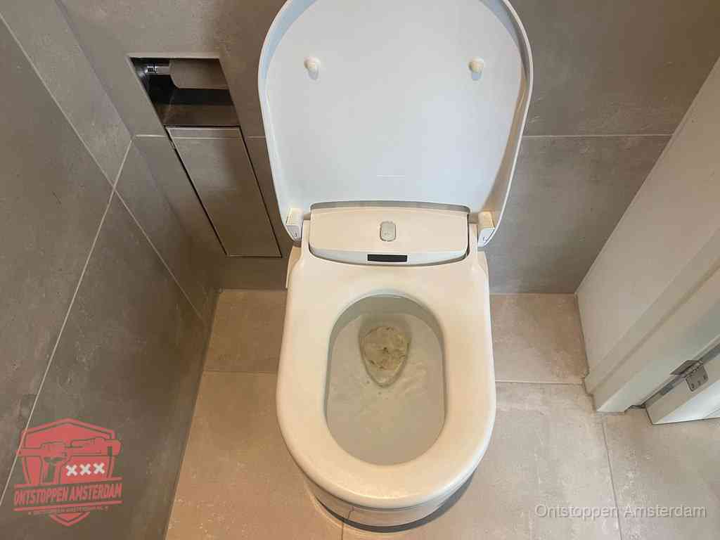 Een wit hangtoilet waarin een prop wc-papier op het water blijft drijven, een duidelijk signaal van een verstopte wc in Amsterdam