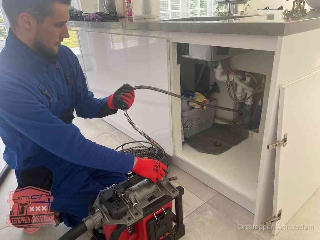 Een monteur reinigt de keukenafvoer grondig met een veermachine om terugkerende gootsteenverstoppingen te voorkomen in Amsterdam