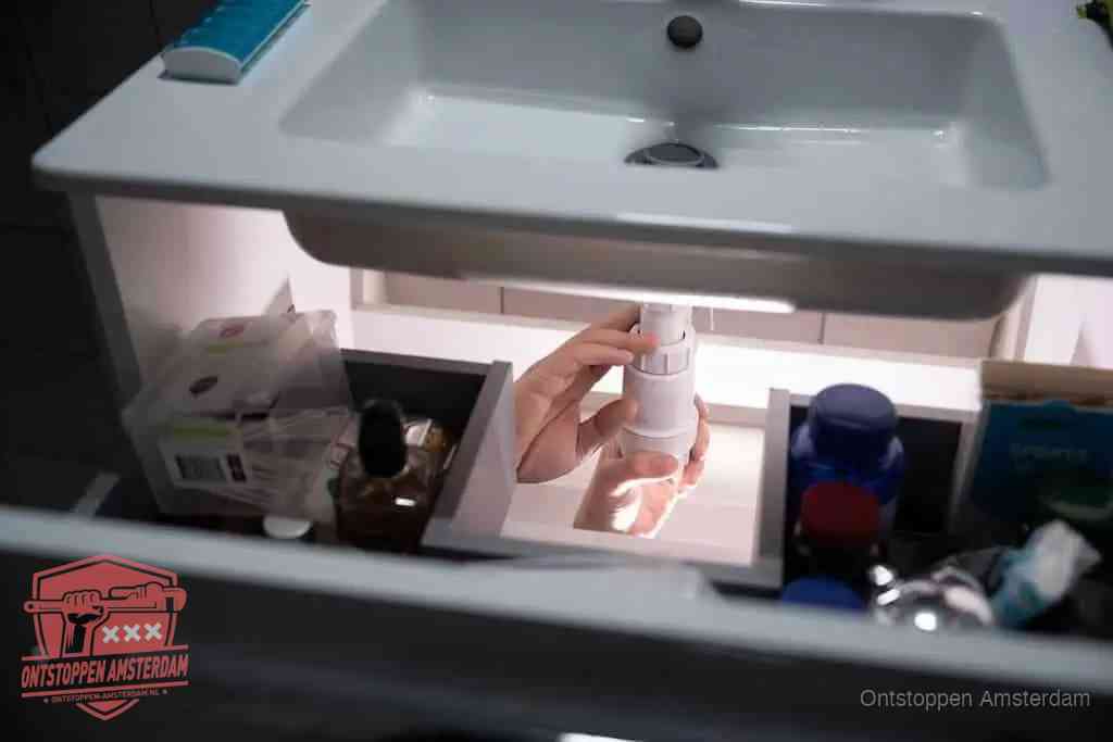 Een pompfles met zeep boven een wastafel in de toiletruimte, de warm water en afwasmiddel-methode om de wc te ontstoppen in Amsterdam