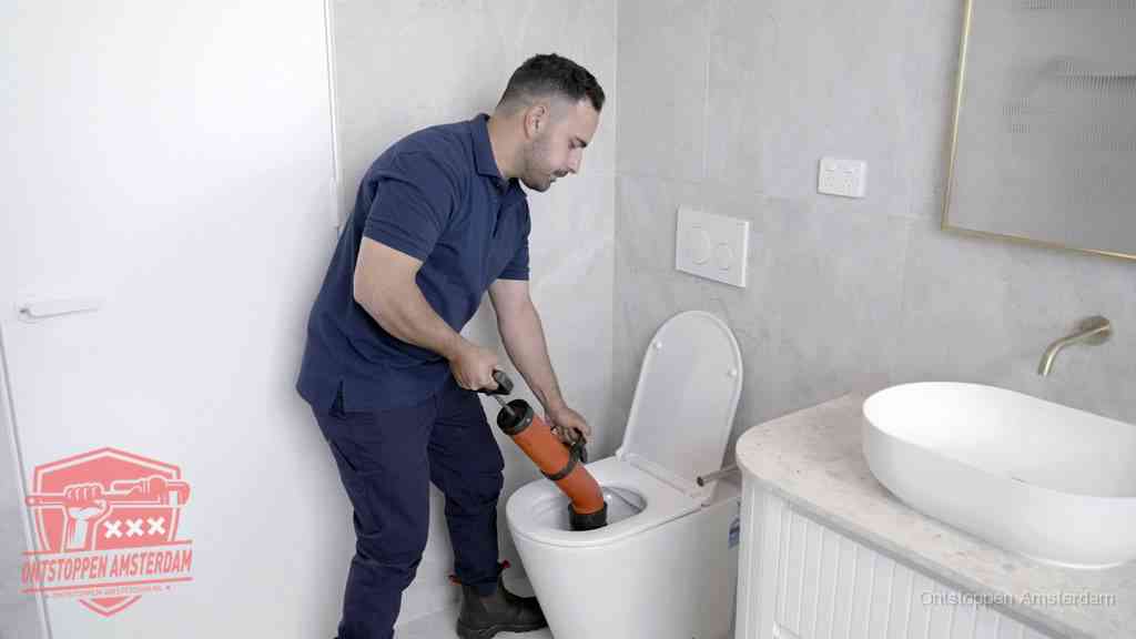 Een monteur gebruikt een handmatige perspomp (toiletontstopper) op een wandcloset tijdens het professioneel wc ontstoppen in Amsterdam