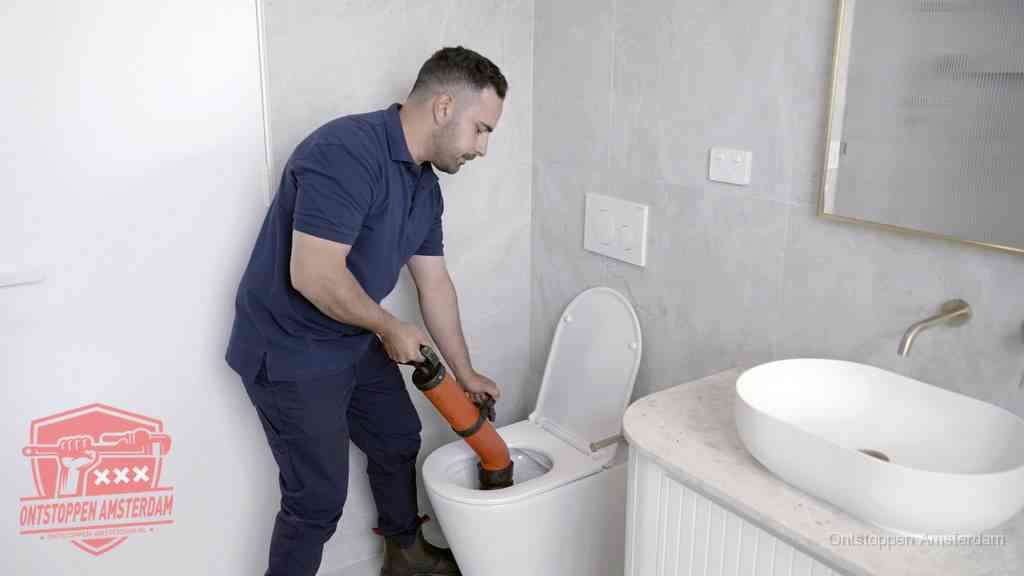 Een man gebruikt een handmatige luchtdruk-ontstopper in een modern betegeld toilet om zelf de wc te ontstoppen in Amsterdam